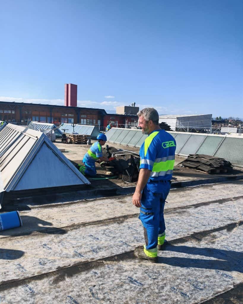 Travailleurs en sécurité sur un toit en rénovation à Genève.