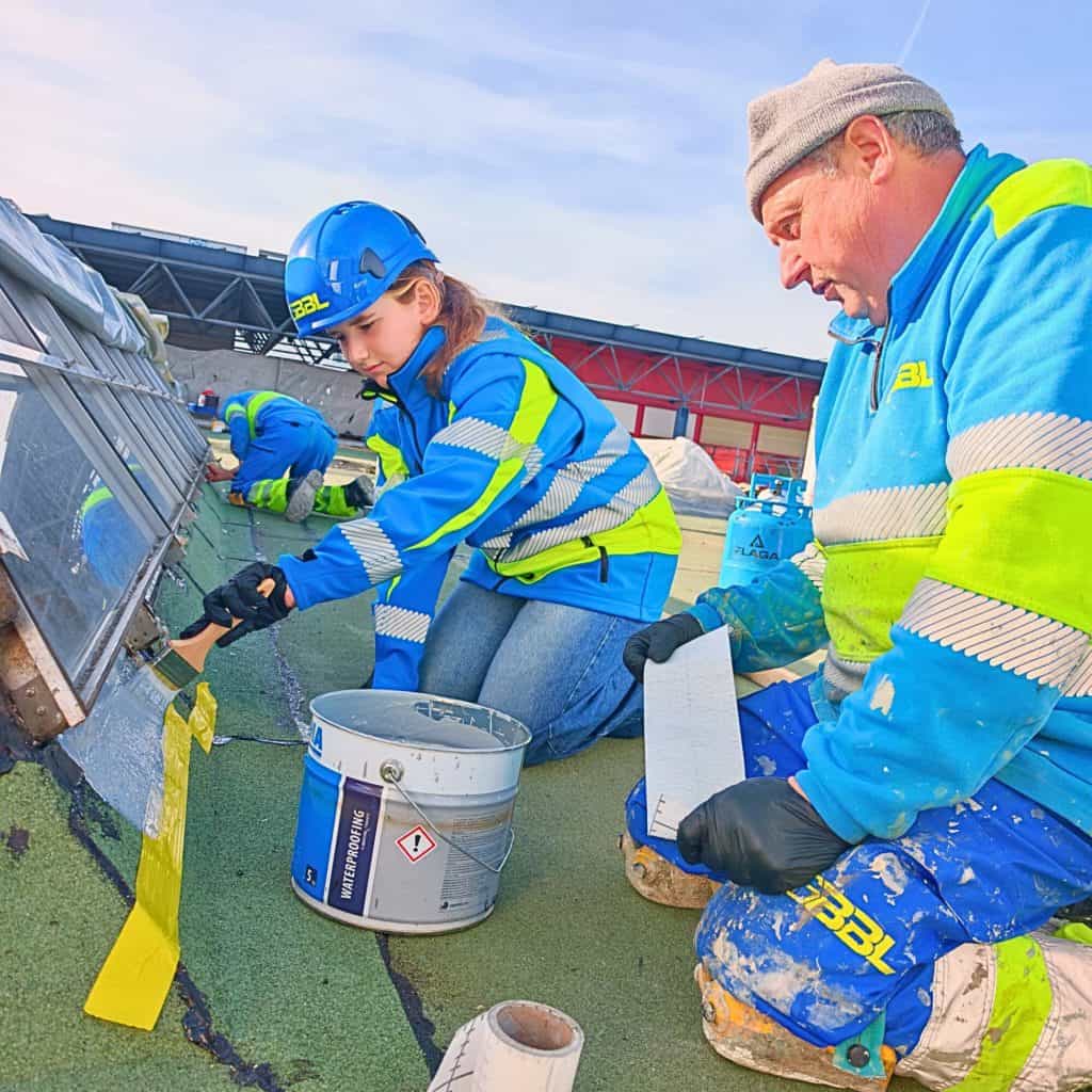 Travailleurs effectuant des travaux spéciaux sur un toit avec équipement de sécurité.