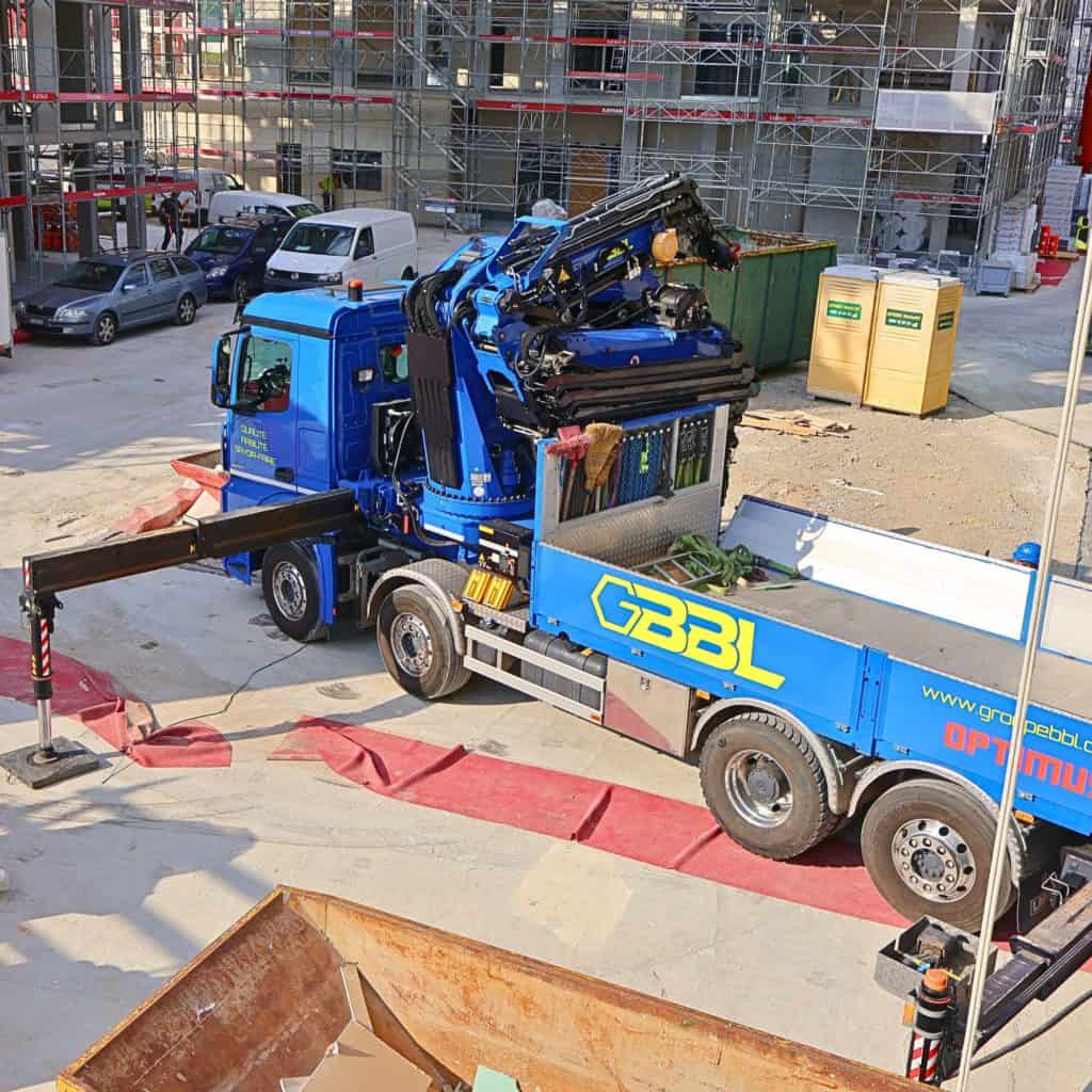 Camion de levage bleu avec grue en action sur un chantier de construction.