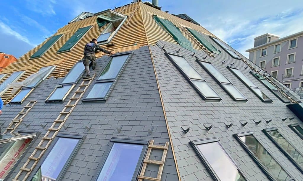 Travaux de couverture et pose de fenêtres sur un toit en rénovation.