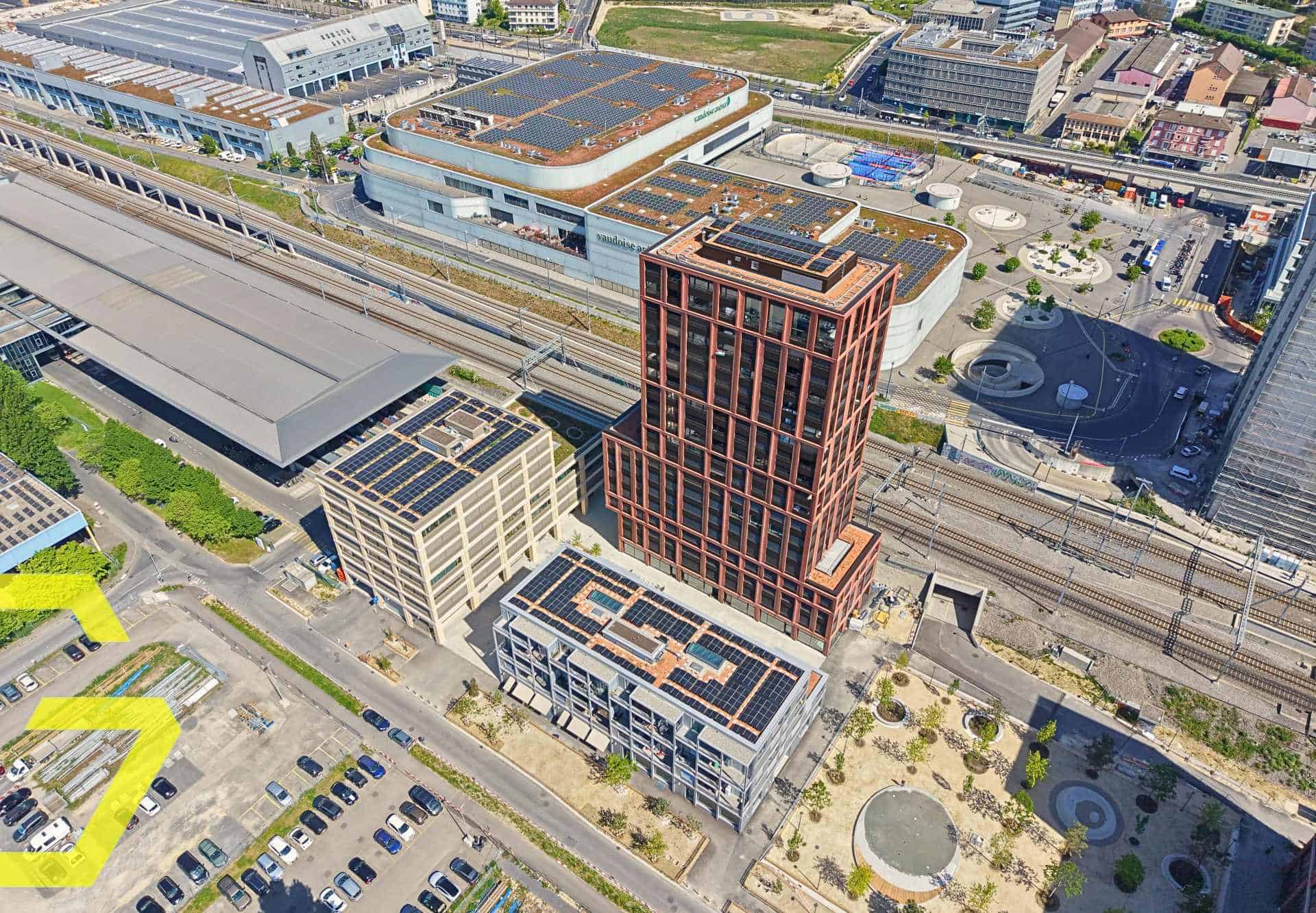 Vue aérienne de la centrale Malley à Lausanne avec bâtiments modernes et gare ferroviaire.