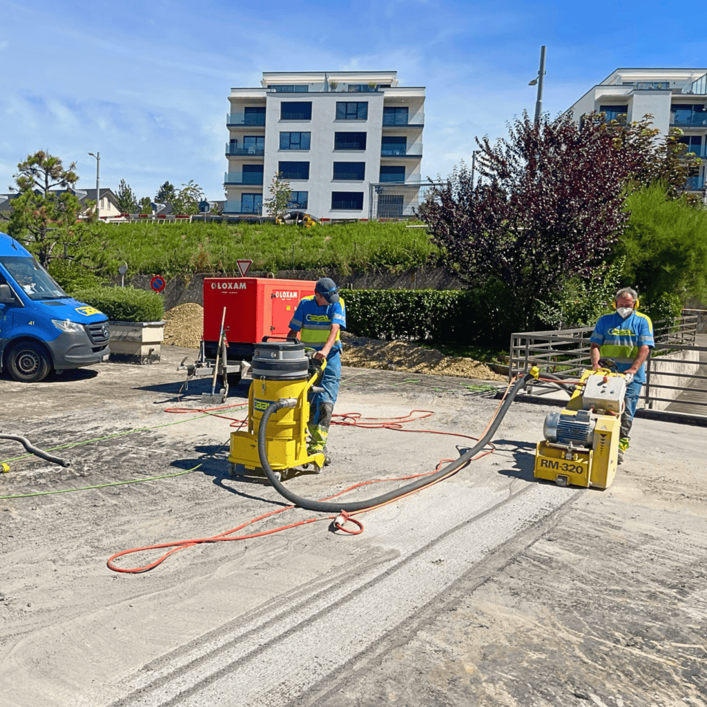Travaux de construction routière par deux ouvriers avec équipements spécialisés.