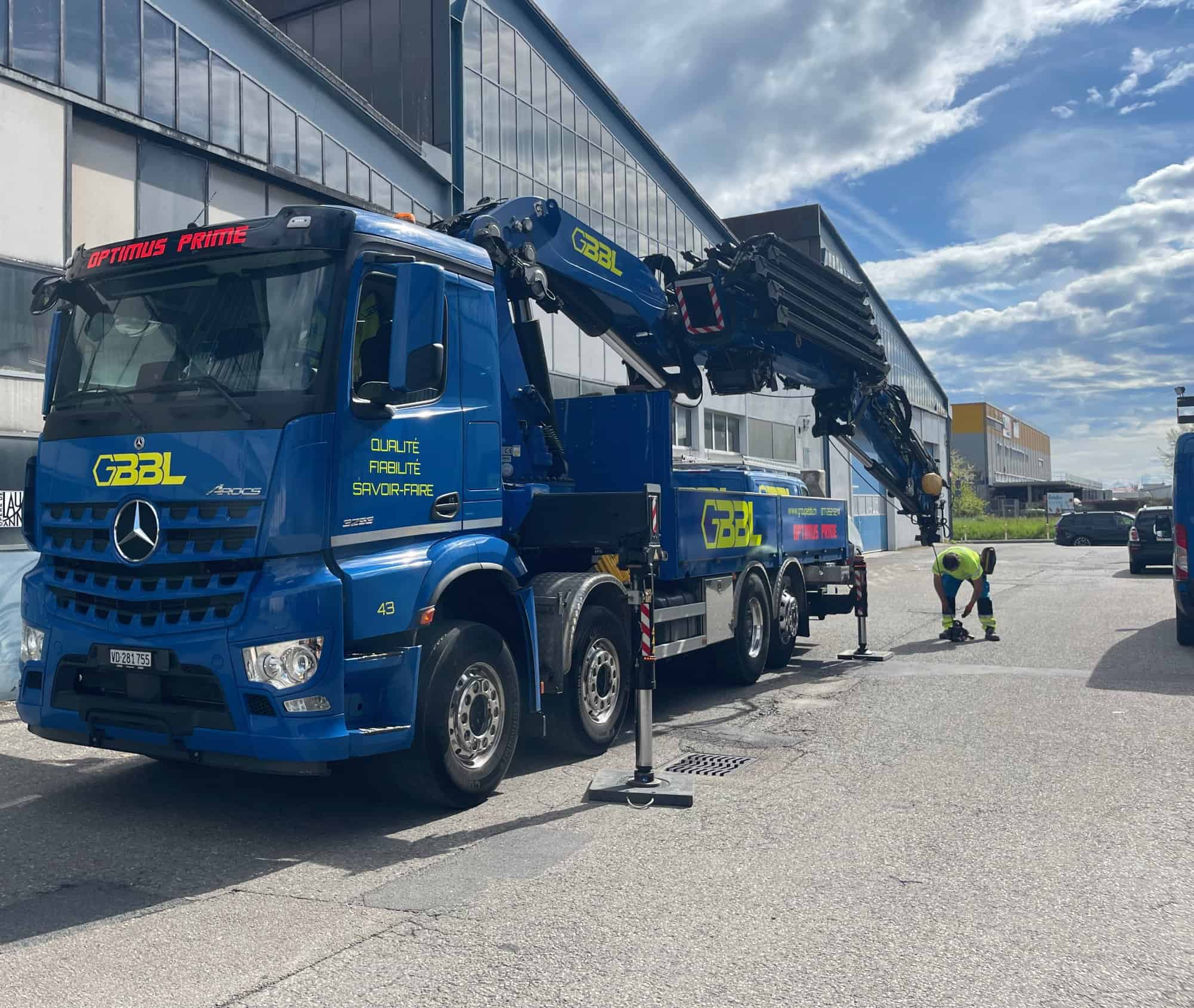Camion de levage Mercedes-Benz avec grue GBL à l'extérieur d'un bâtiment industriel.